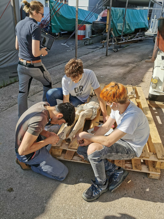 Jesus_restauration _6_-Jugendliche von Job Ahoi arbeiten an der Christusfigur_ Restauratorin Nicole Mayer u__berwacht die Ar.jpg