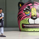 Eine Arbeiterin putzt neben einer Tiger Dekoration für Chinesisch Neujahr in Thailand.