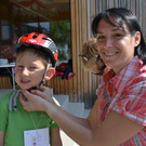Radhelmspielefest 114 Kindergartenassistentin Sonja Beyrer mit Felix bei der Helmeinstellungsstation_JPG-1367917680
